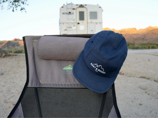Blog post: Meet the Makers - Rest & Roam hat on camp chair behind camper on the beach