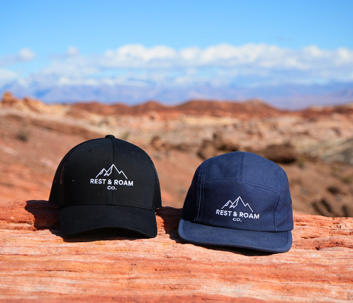 The Rest & Roam Co. Hat Collection - trucker style and 5-panel hat positioned on red rocks at Valley of Fire
