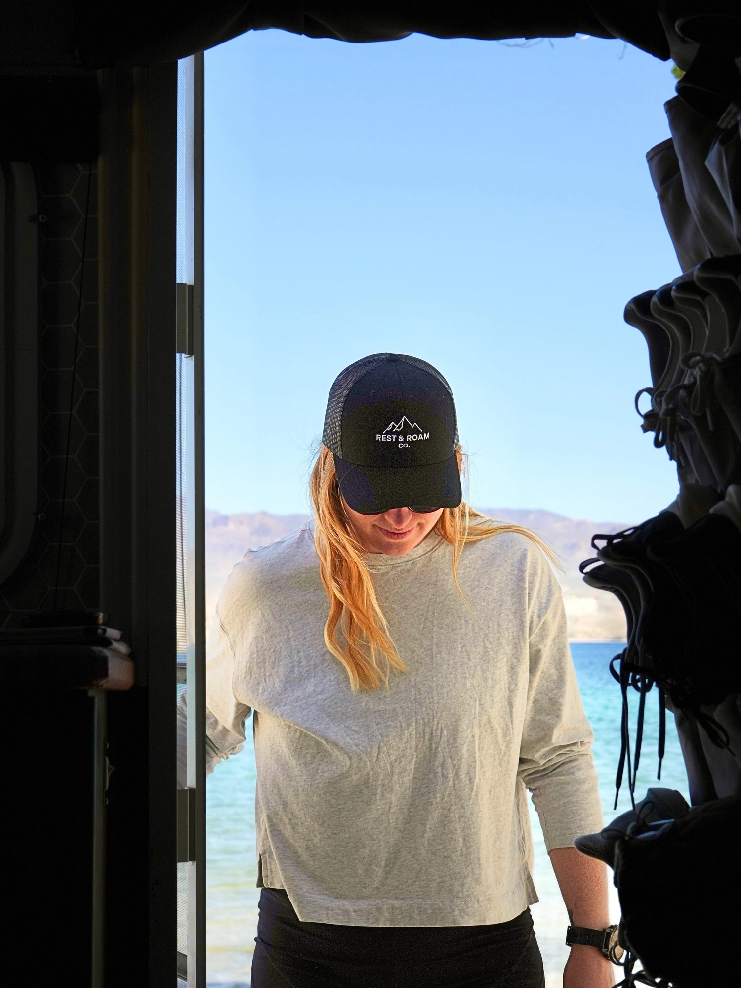 A woman wearing The Classic Trucker Hat in a door way near the Colorado River.