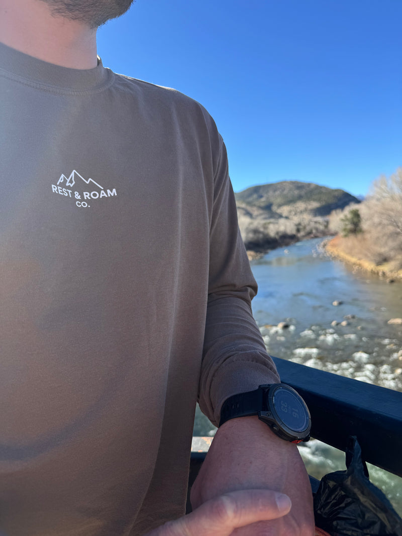 Man standing next to the Animas river wearing the Unisex Rest & Roam Co. Long Sleeve shirt (The Foxy)