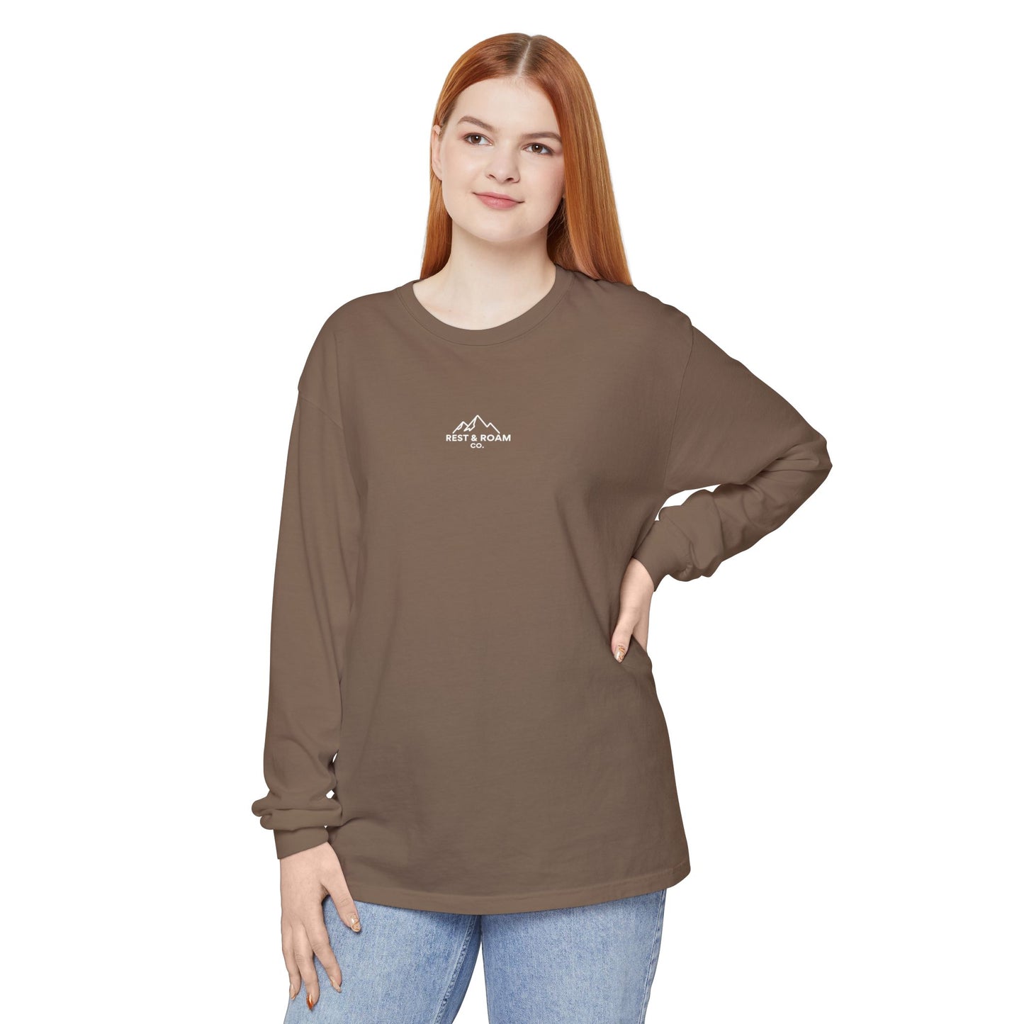Woman wearing a brown long-sleeve (The Foxy) Rest & Roam Co. shirt and blue jeans on a white background