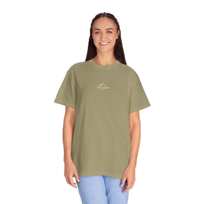 Person wearing a green t-shirt with Rest & Roam Co. design on a white background